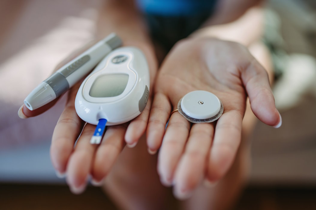 Close up of hands with diabetes supplies and devices.